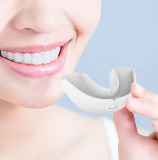 Femme tenant la gouttière anti-ronflement en silicone blanc près de son visage
