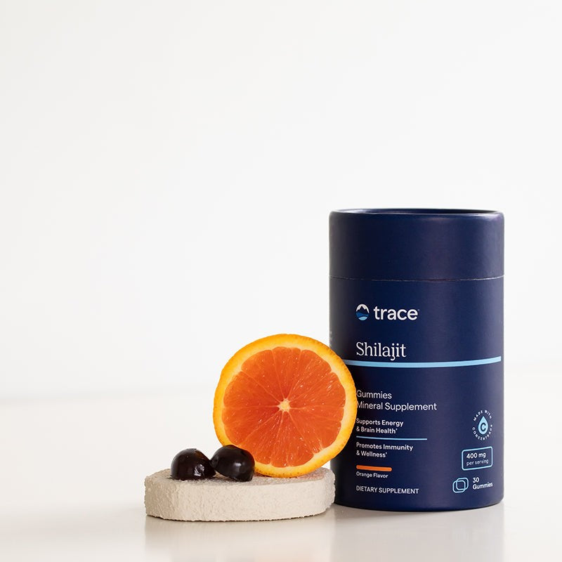 Tube de gummies au shilajit avec une orange et deux gummies posés à côté