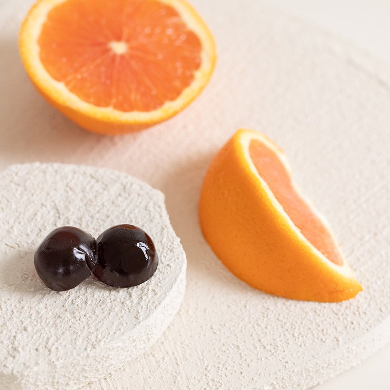 Gros plan sur les gummies au shilajit et des quartiers d'orange